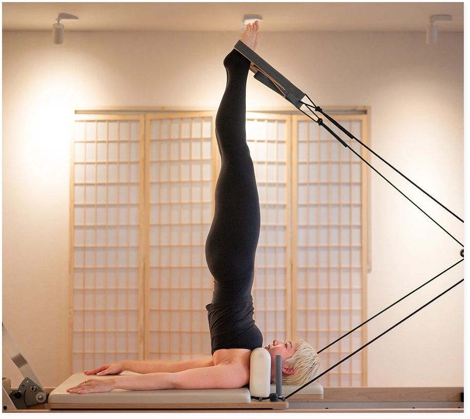 ピラティスマシンで足をあげているピラティスインストラクター